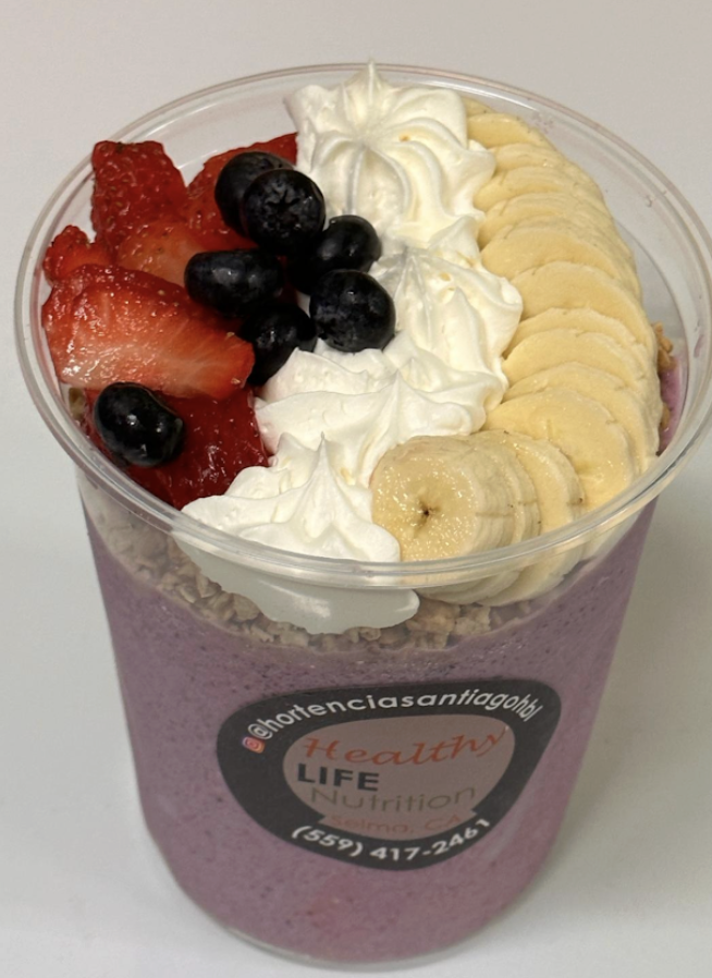 Berry bowl topped with granola, strawberries, blueberries, banana slices, and whipped topping.