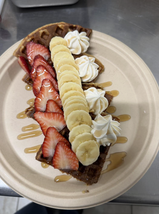 Protein waffle topped with strawberries, banana slices, and whipped topping.